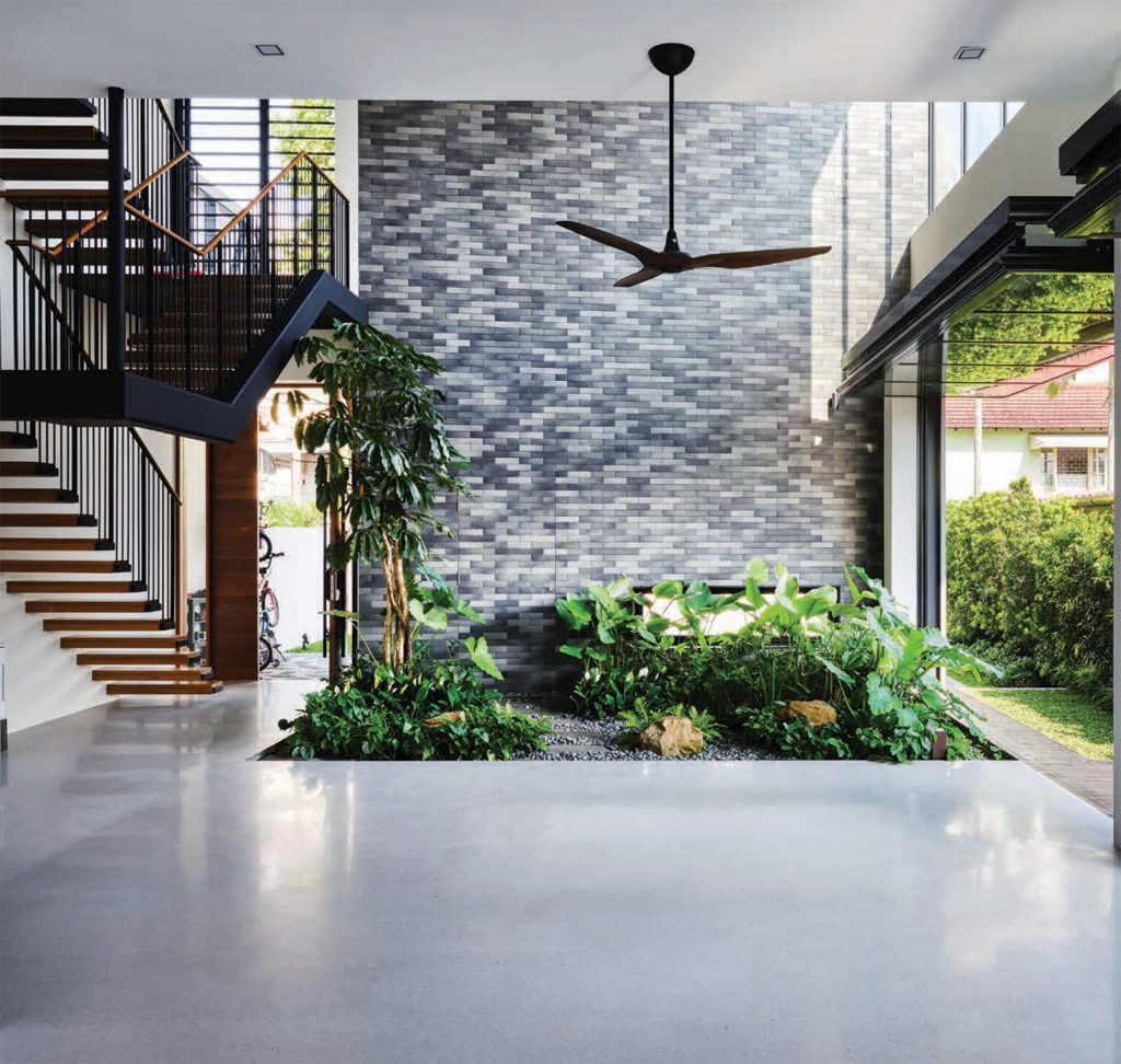 A beautiful two-story home in Singapore featuring multiple glazed folding doors with a small indoor garden