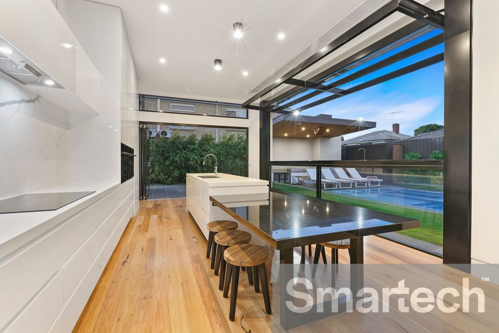 a beautiful natural white kitchen with a black table centre island. A large 6 pane tilt window open sitting beneath the ceiling.