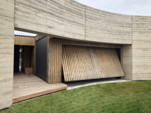 a custom timber clad facade garage door begins to open into a court yard of grass