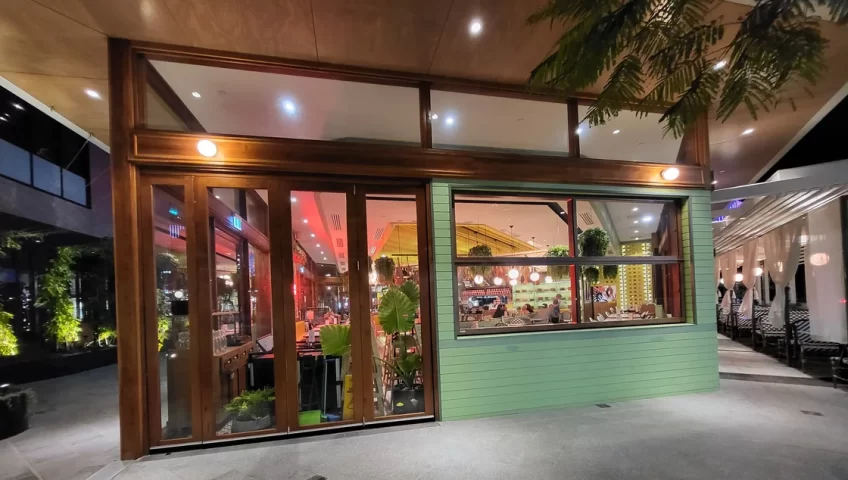 A sophisticated dining setting at Spice Market Thai restaurant in Karrinyup, WA, featuring Smartech's Folding Windows with a rich wood-grain appearance, seamlessly blending with the venue's timber aesthetics and providing a functional, open-air ambience.