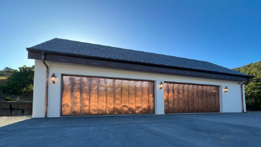 two garage doors clad in copper sheeting glistening in the sun.