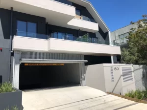 Modern apartment building with a garage entrance, featuring a facade with vertical slats and a height clearance sign of 2.1 meters.