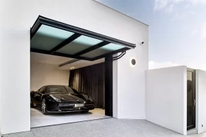 Modern garage with a sleek black car parked inside, featuring a triple-pane glazed tilt wall door in an open position. The door design adds a stylish and functional element to the building's exterior.