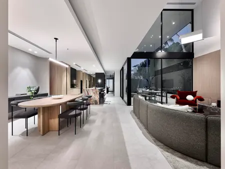 Modern open-plan living and dining area with large windows, featuring a triple-pane glazed tilt wall that offers plenty of natural light and a seamless connection to the outdoor space.