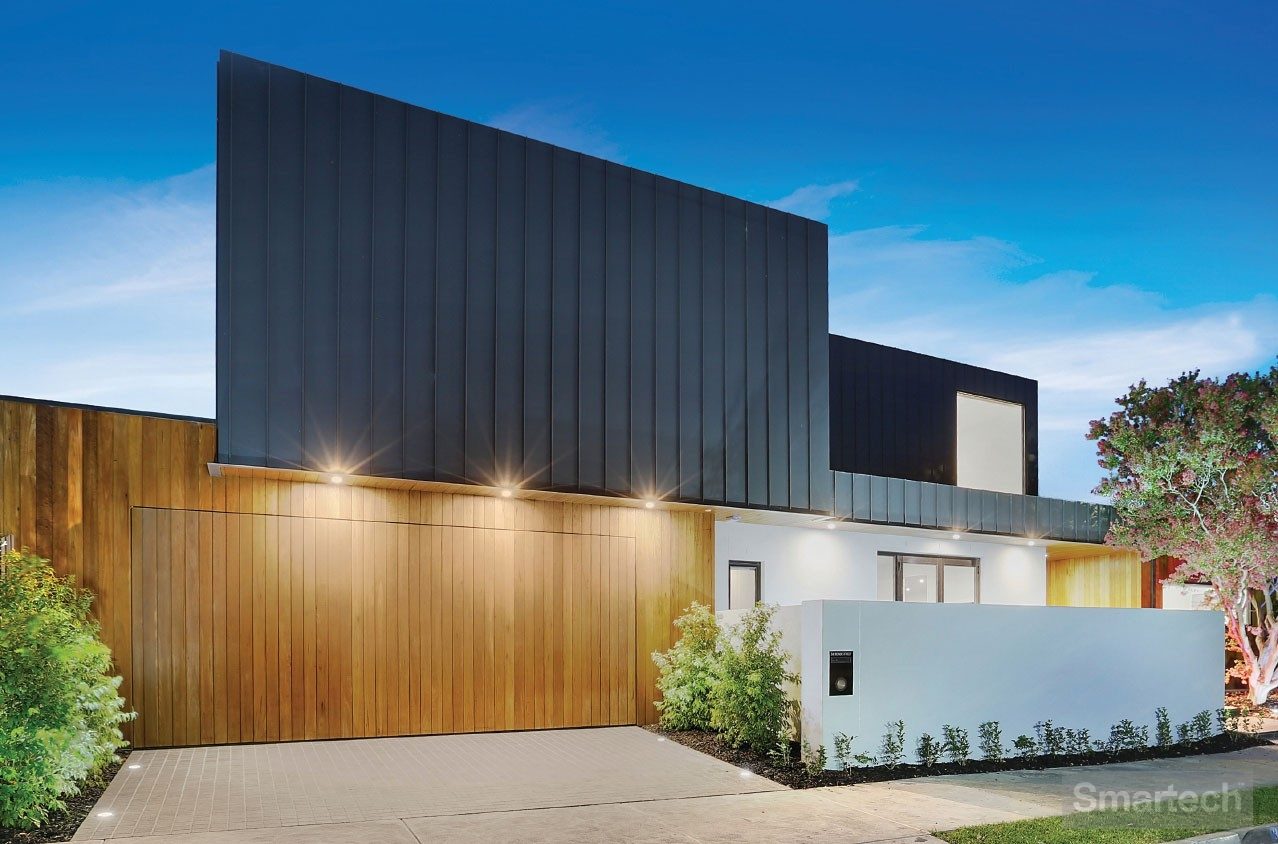 Flush Finish Facade Tilt Garage Door featuring a beautiful architectural home with shrubs lining the driveway